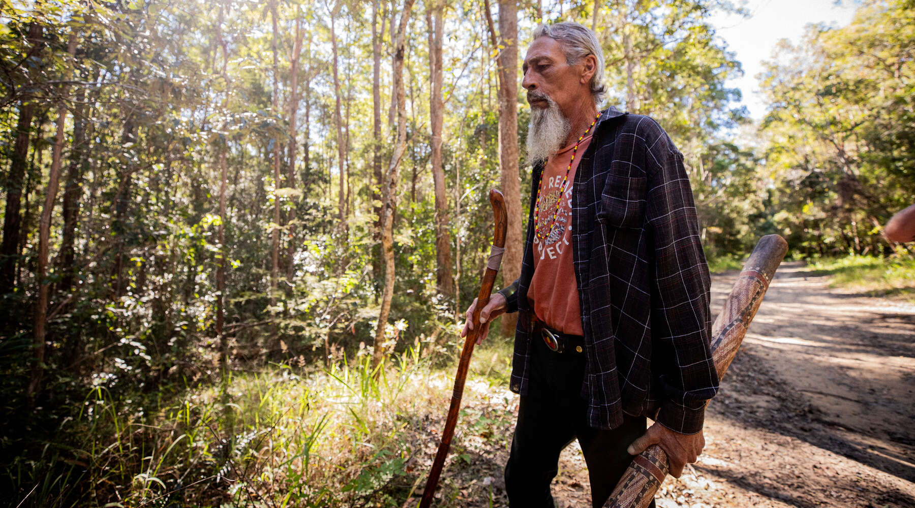 uncle kevin starkey walking inthe forest holding digeridoo