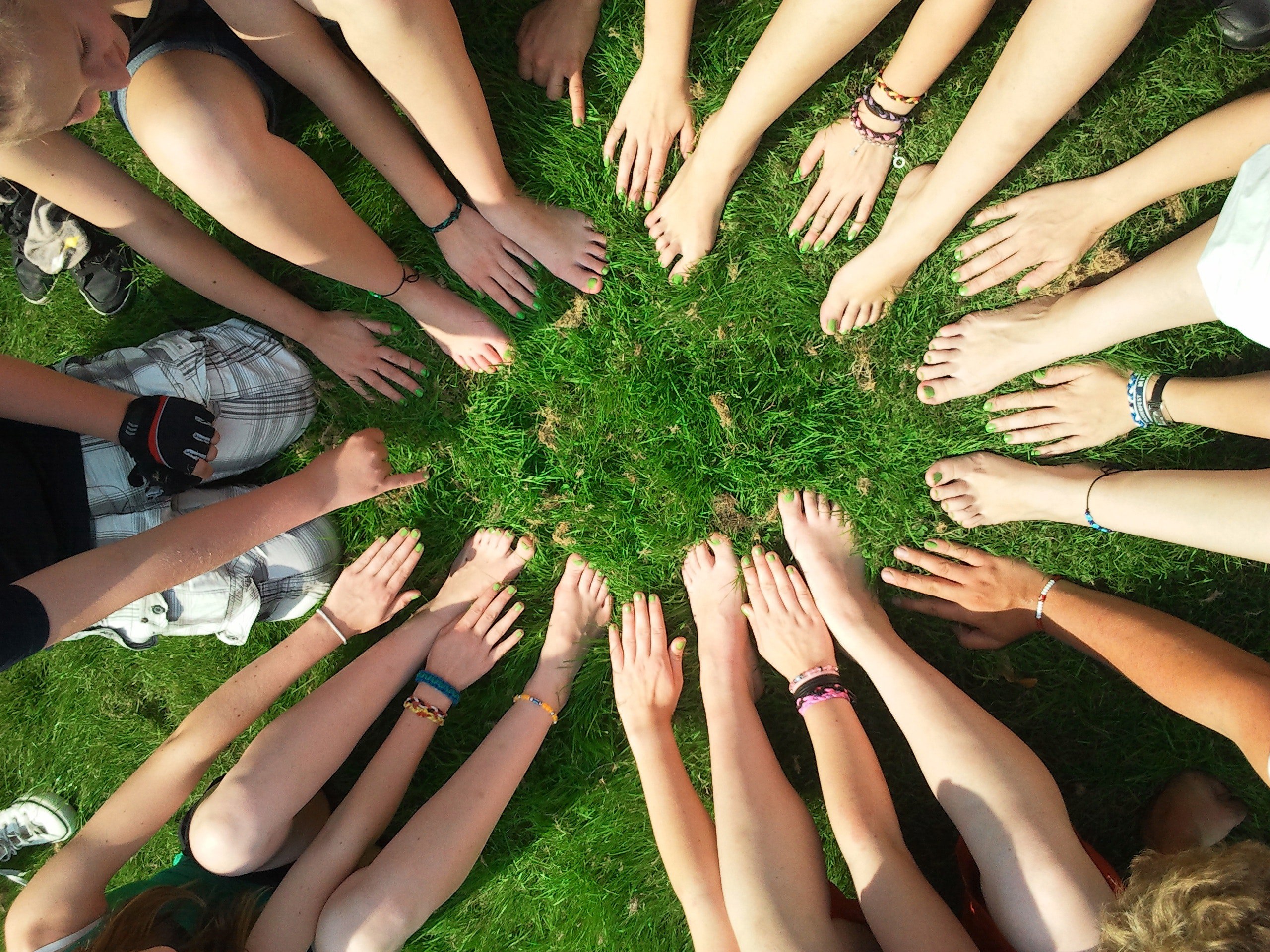 many hands and feet forming a circle on a green grass