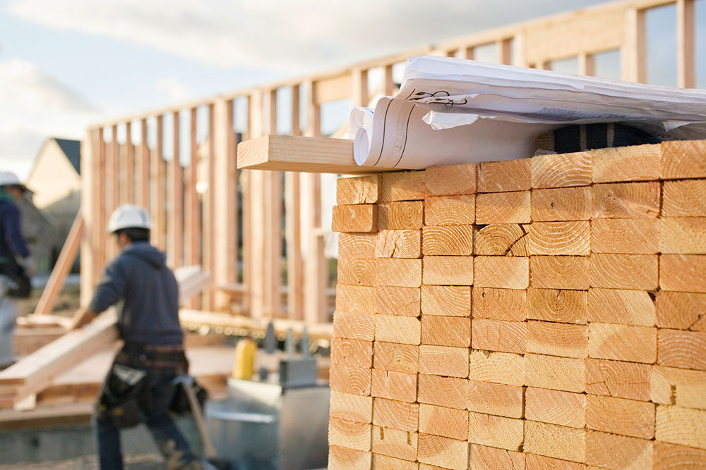 Stacked lumber and blueprints at a construction site