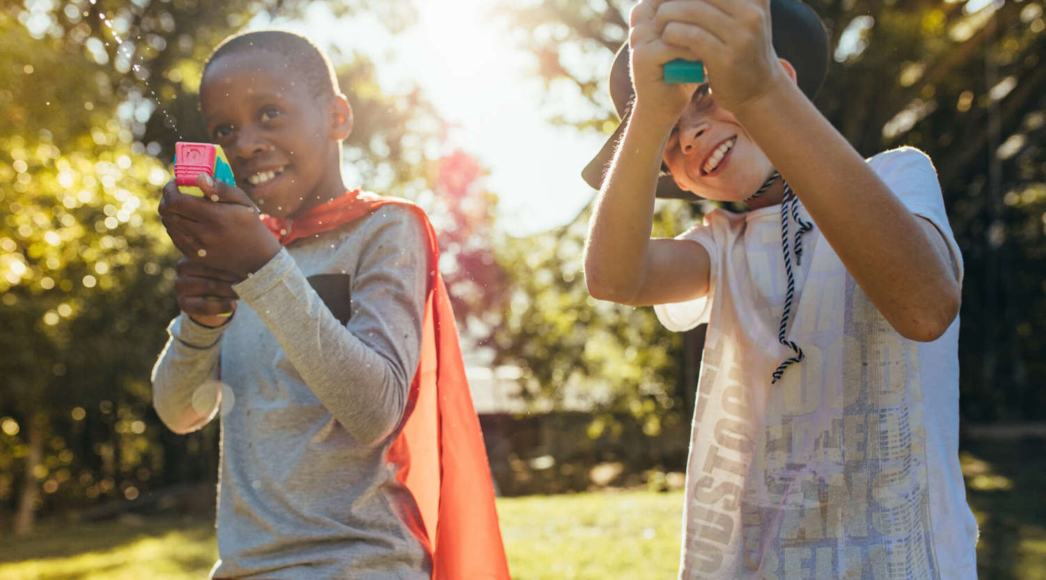 two boys playing with water pistols