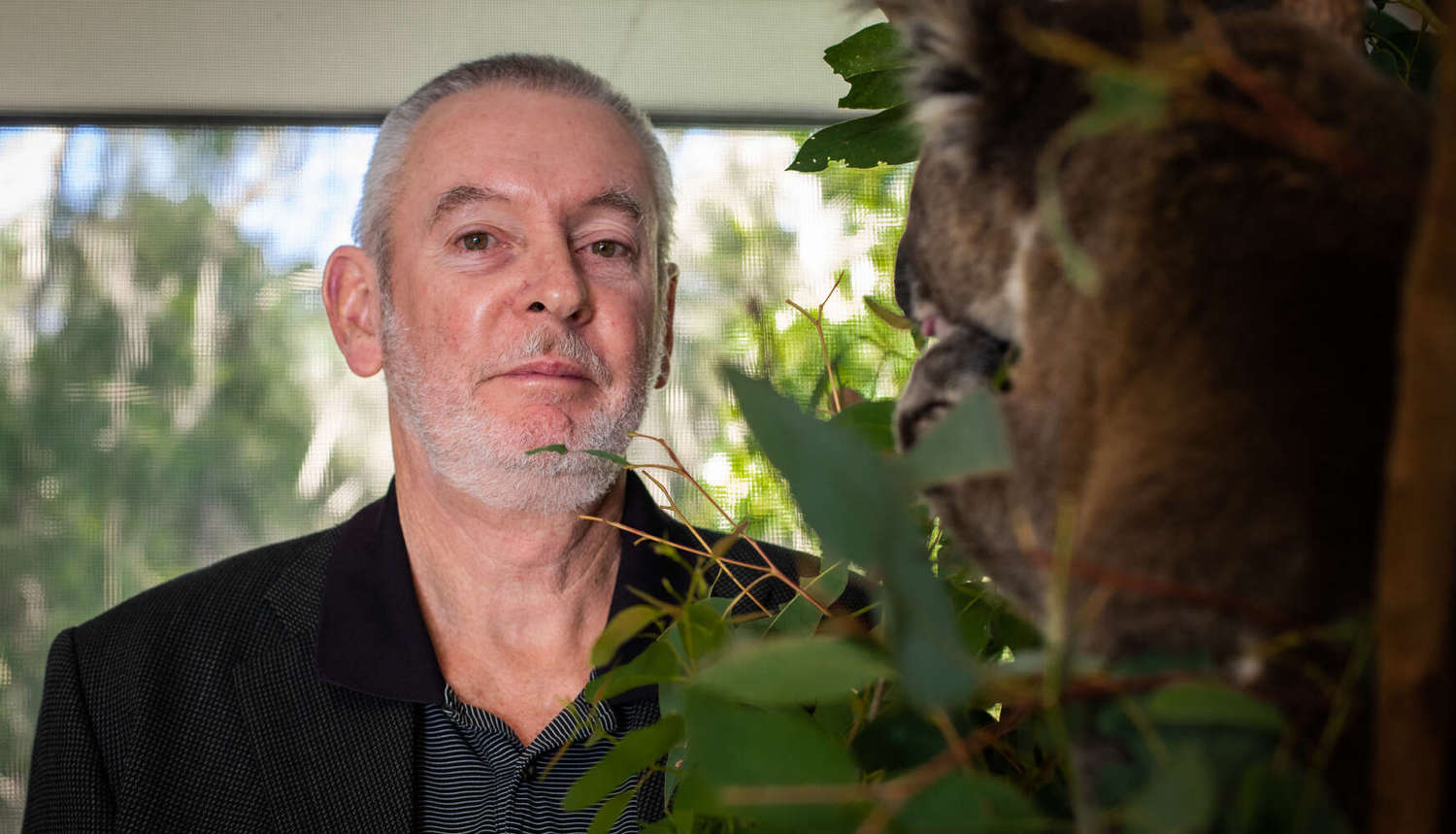 professor peter timms standing next to a koala