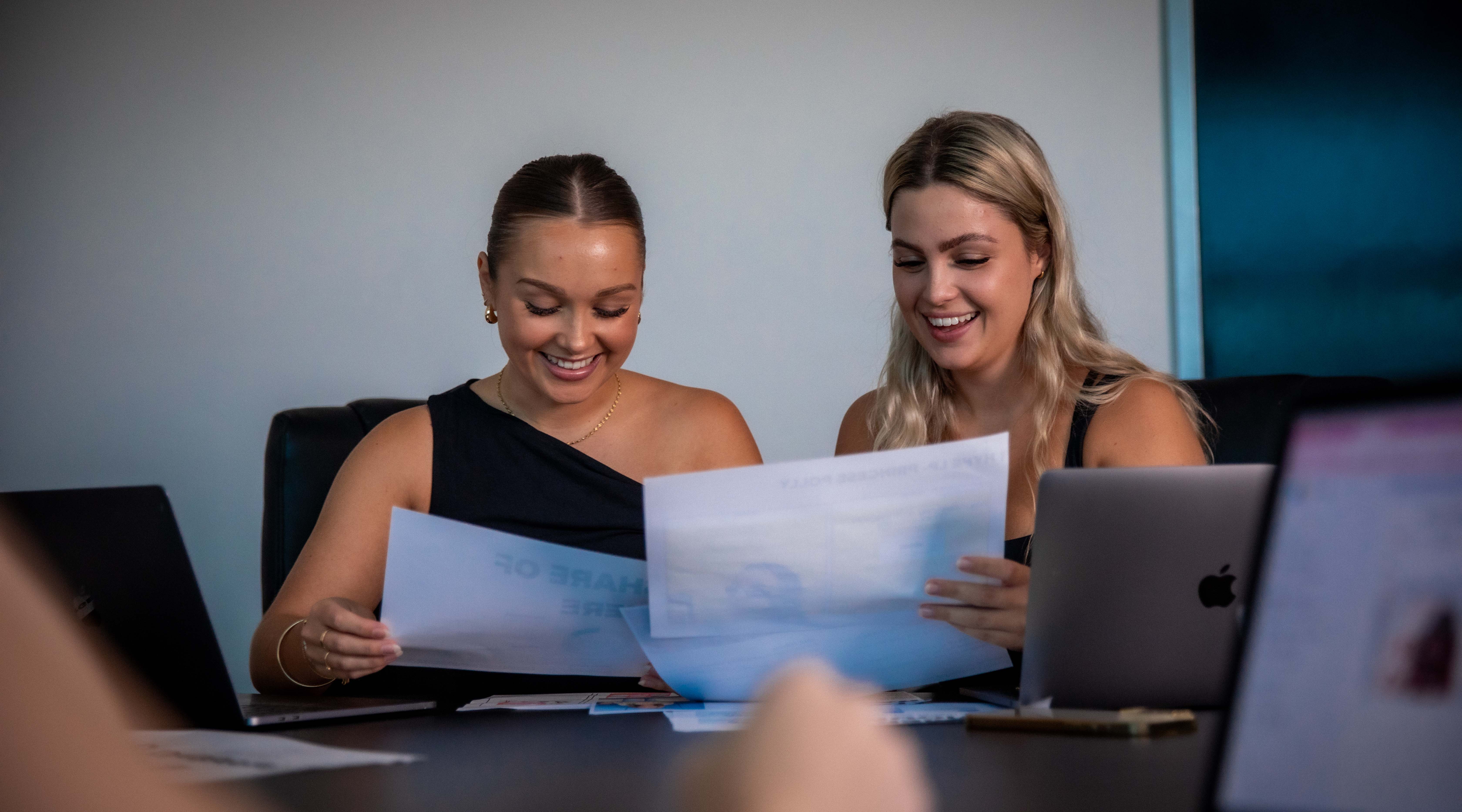 Liv is looking at some papers with a colleague, they are both laughing. 