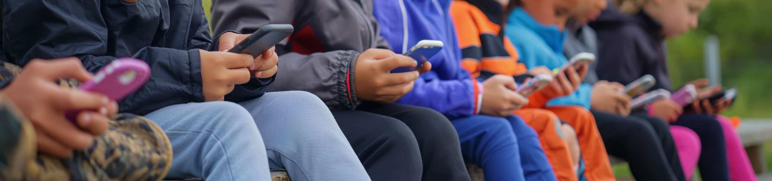 row of children all looking at their mobile phones