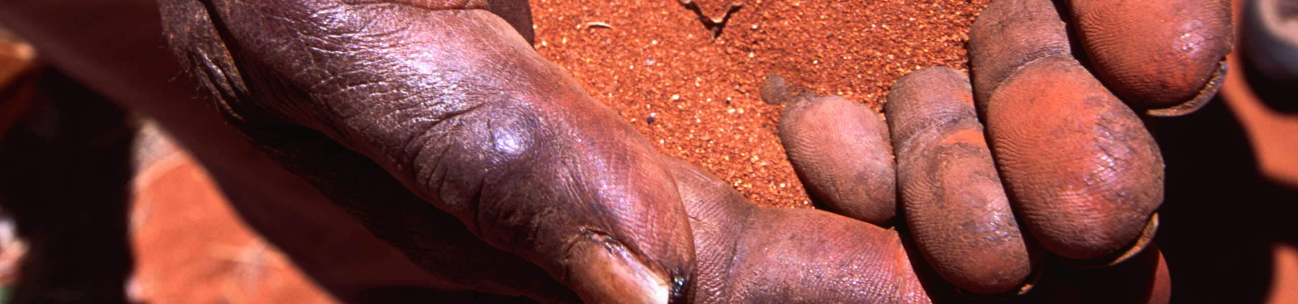 Indigenous hands holding red sand