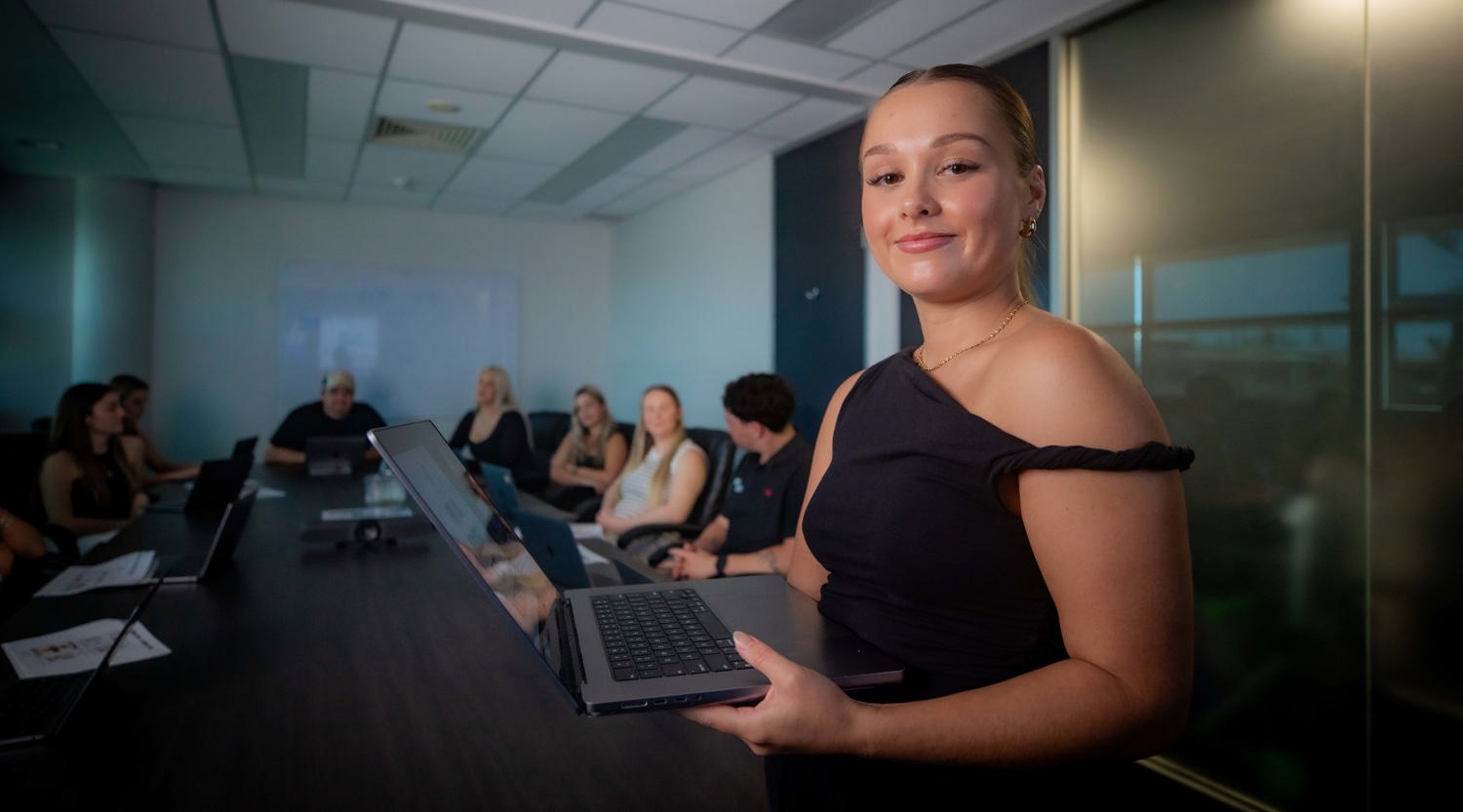 Liv stands in the foreground of a photo running a meeting at Growth Huntr