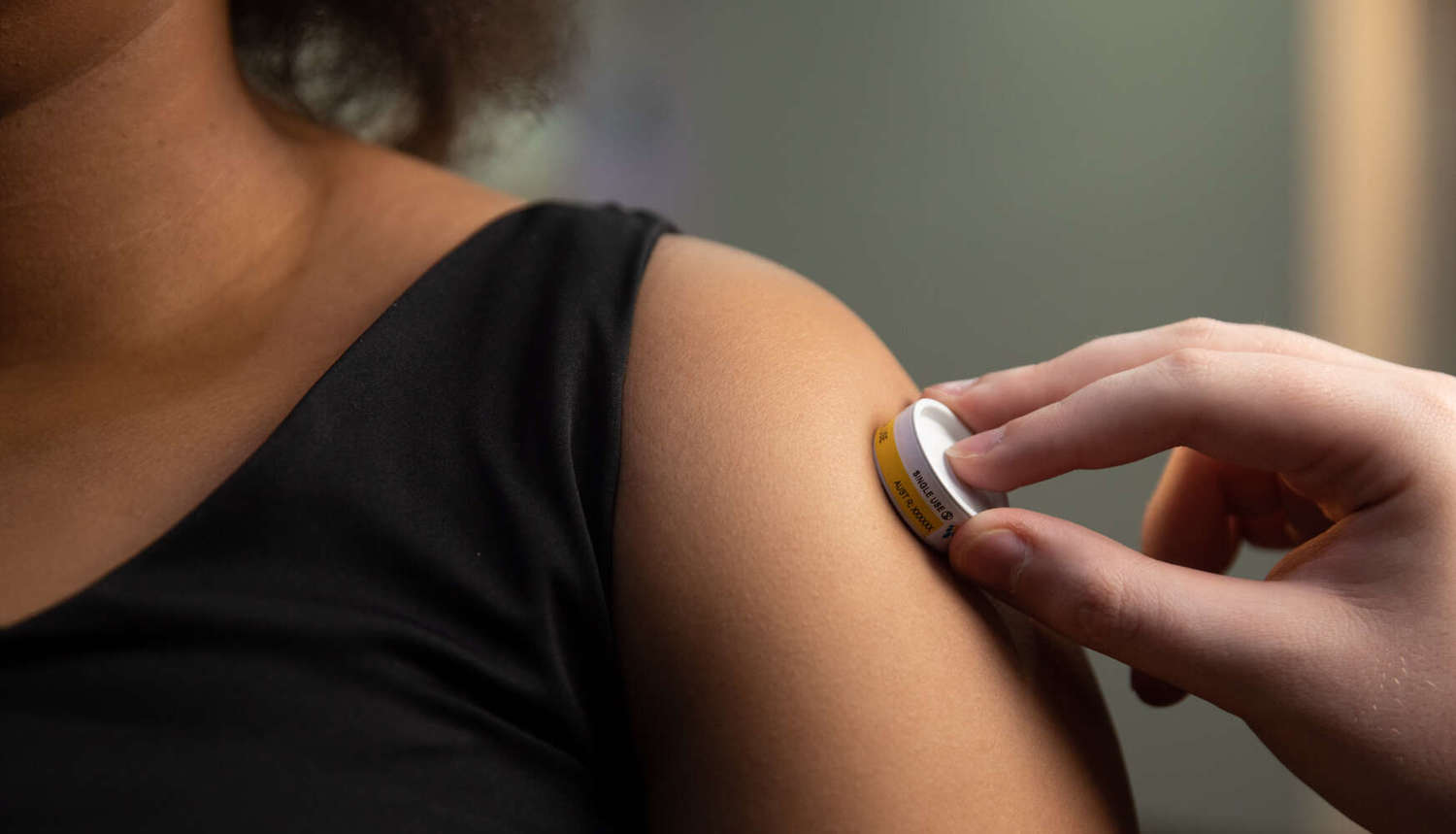 influenza patch being placed on a person's upper arm