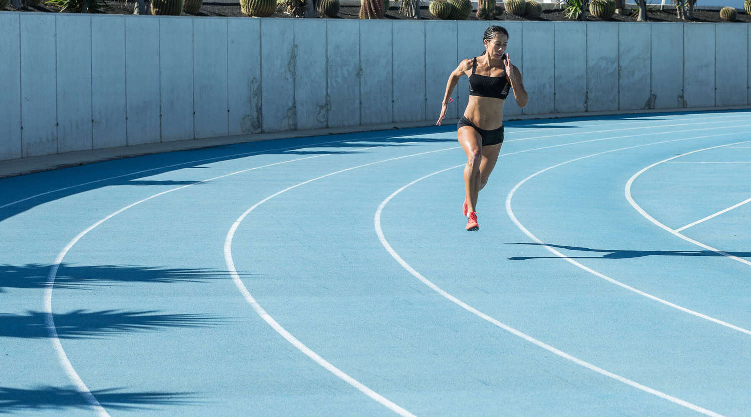 female runner sprinting on athletics track