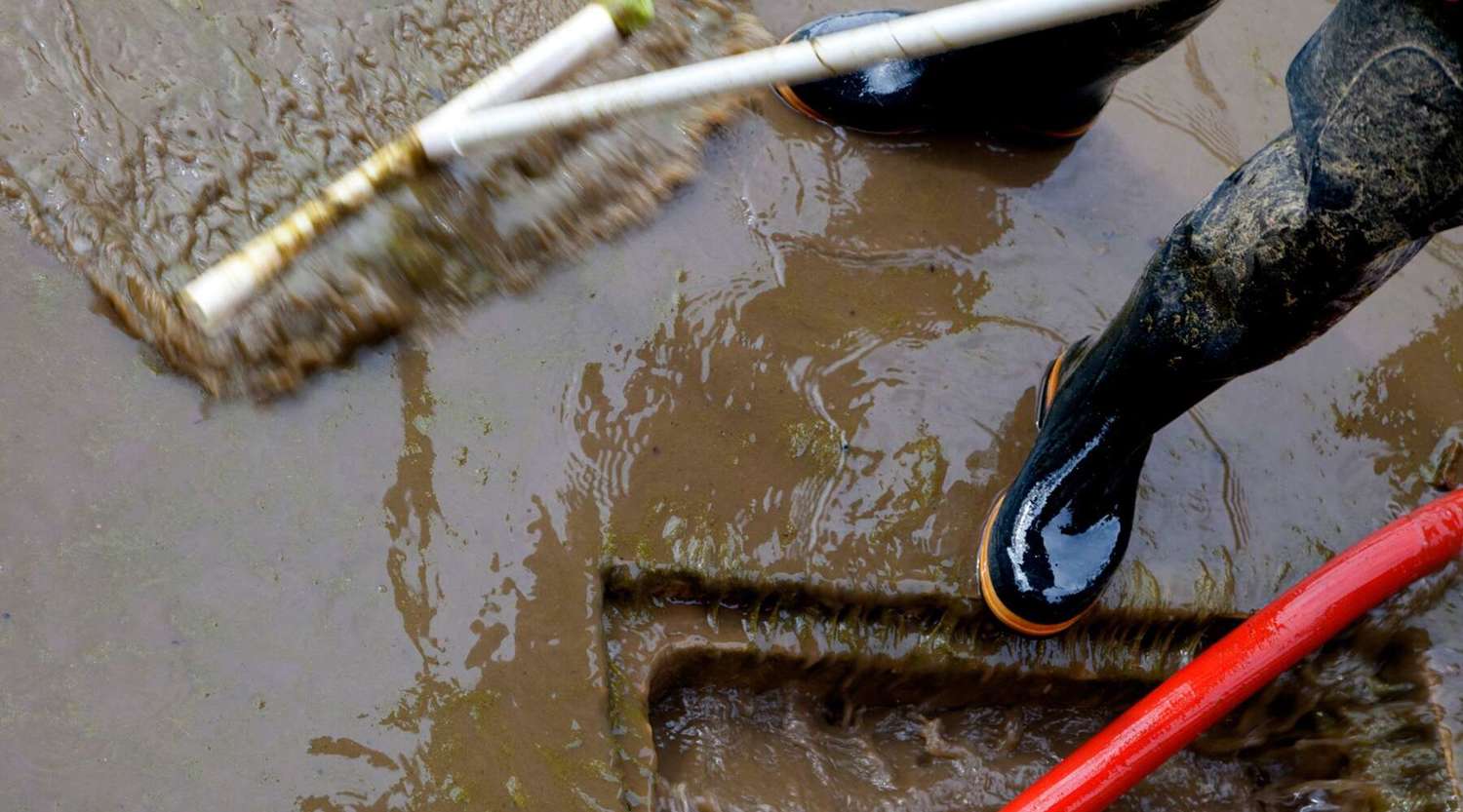 person in gumboots sweeping water