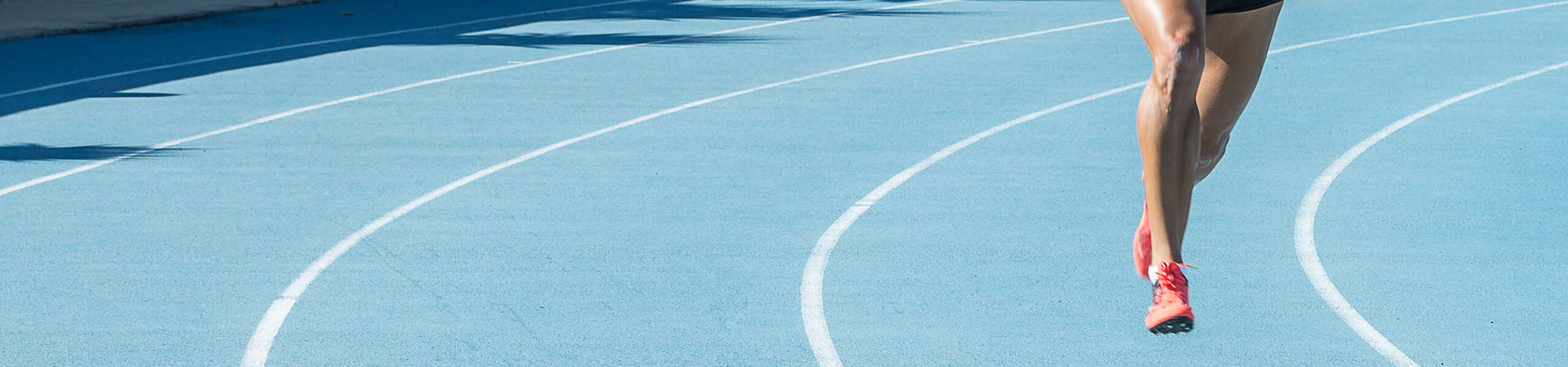 female runner sprinting on athletics track