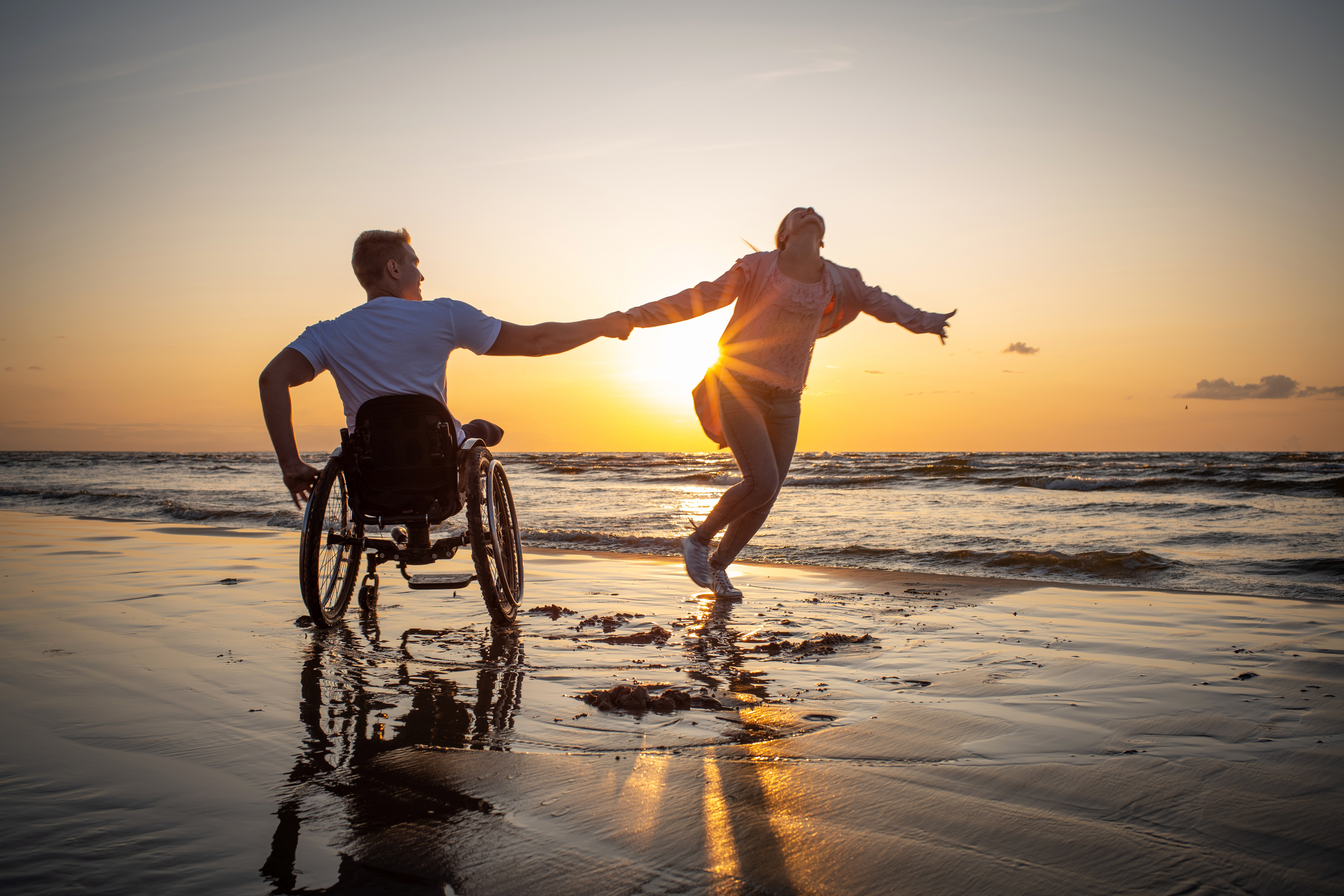 Man in wheelchair and woman on the beach