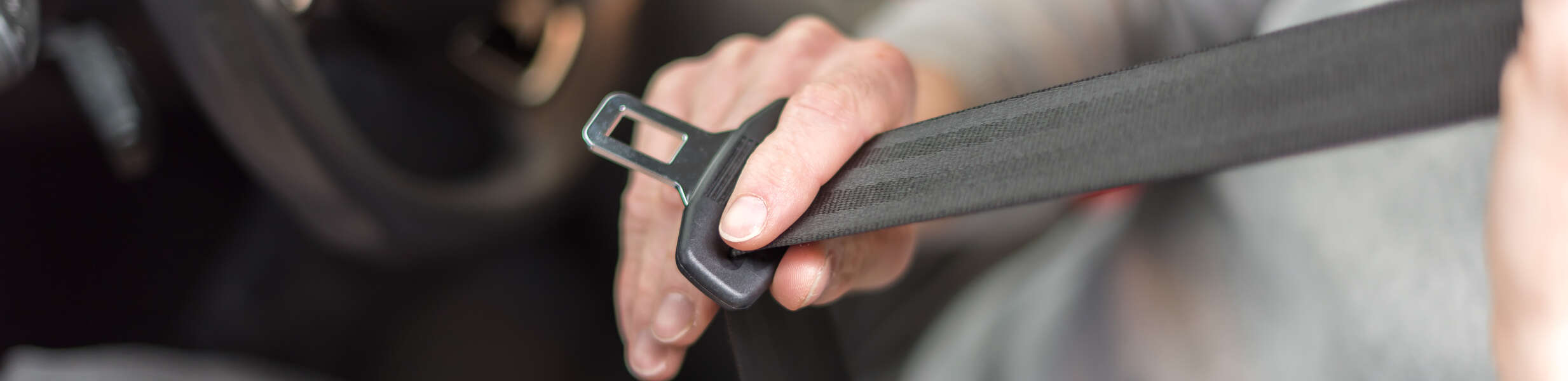 person putting on seat belt in a car 