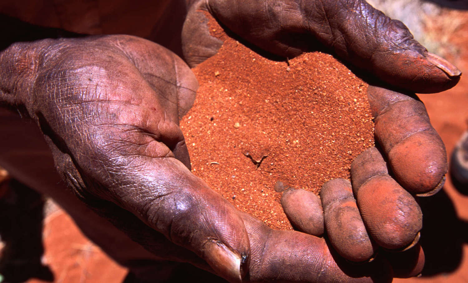 Indigenous hands holding red sand