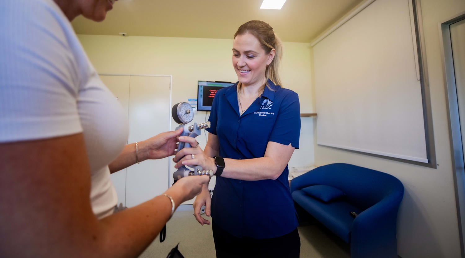 Occupational Therapy student Elizabeth Schahinger and a teacher are handling specialised equipment with a gauge on it