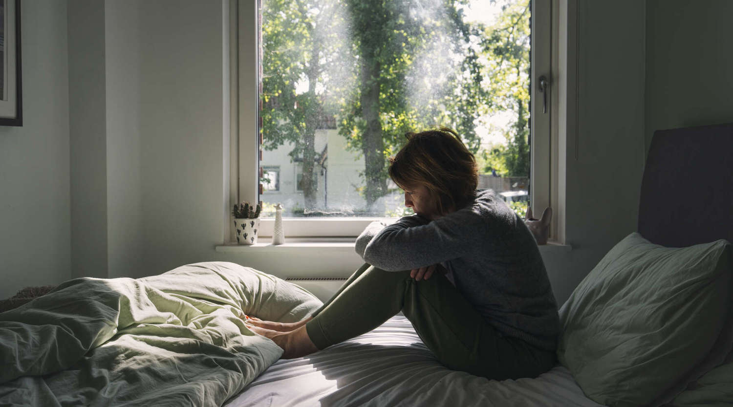 person sitting on the bed looking depressed